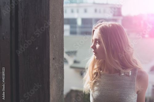 Pretty girl in fashionable grey dress on balcony