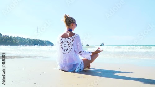 junge, blonde Frau macht Yoga am Strand