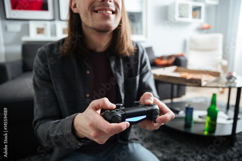 Concentrated man sitting at home indoors play games with joystick.