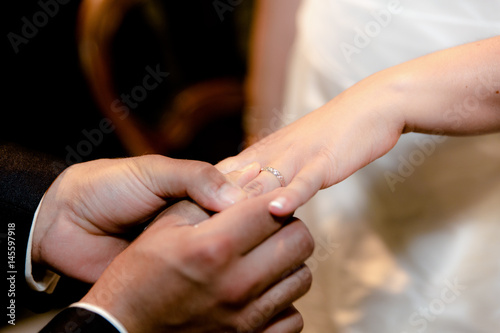Close up hands of bride and groom putting on a wedding rings © NizArt