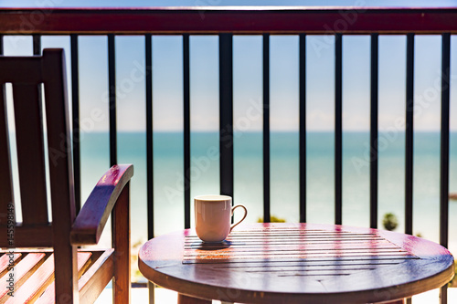 coffee cup on wooden table and chair at balcony with sea view ,concept of relaxing and vacation photo