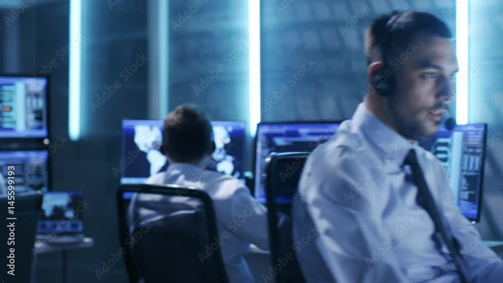 Panoramic Shot of Professionals Working in System Control Center Full of Displays with Various Data and with it's own Server Racks. Shot on RED EPIC-W 8K Helium Cinema Camera. Panoramic Shot of Professionals Working in System Control Center Full of Displays with Various Data and with it's own Server Racks. Shot on RED EPIC-W 8K Helium Cinema Camera.