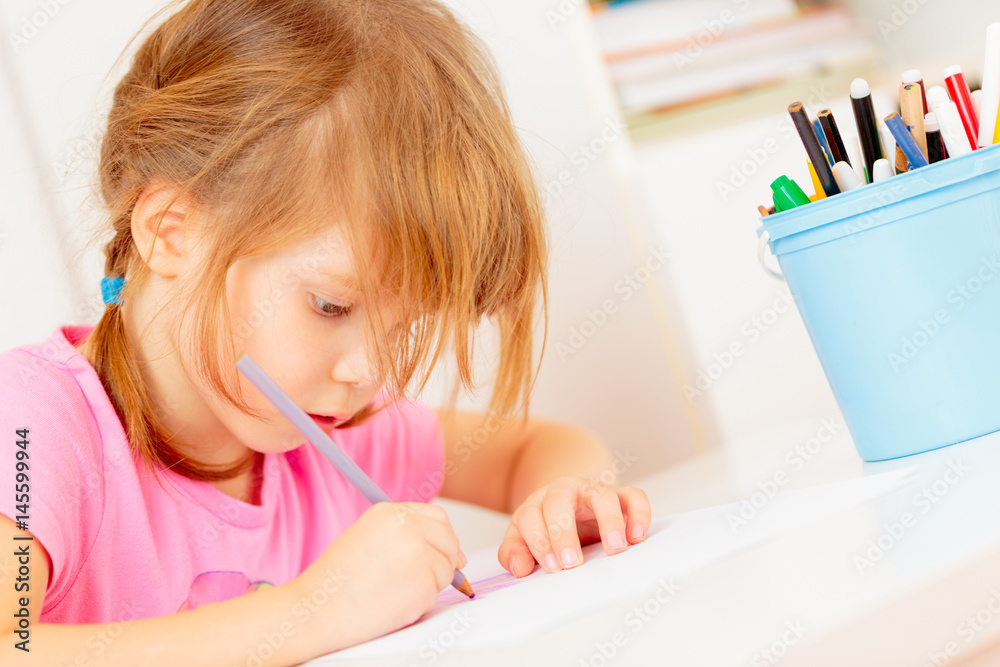Small girl drawing with colourful pencils