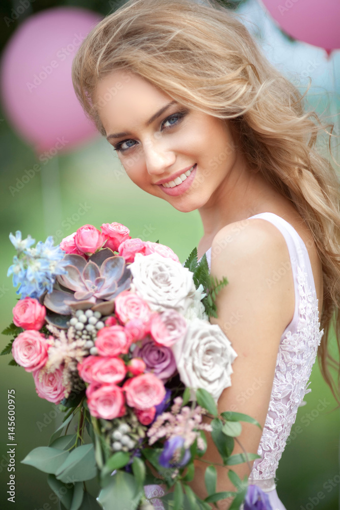 Naklejka premium Beautiful young girl with a bright bridal bouquet on a nature background in summer
