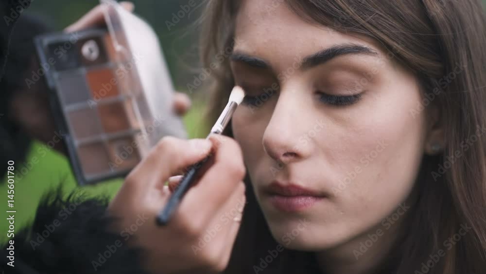 Make up artist's applying eyeshadow  with a brush on woman's eye
