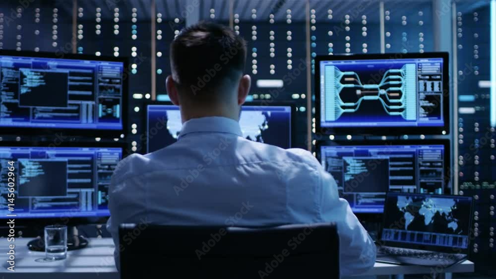 Technical Controller Working at His Workstation with Multiple Displays. Displays Show Various Technical Information. He's Alone in System Control Center.Shot on RED EPIC-W 8K Helium Cinema Camera.