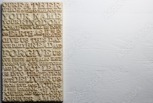 The Lord's Prayer. Wooden carved word of the Lord's Prayer on white weathered wooden background.