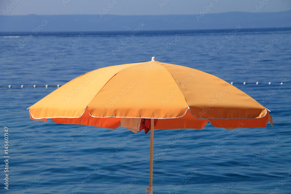 Orange beach umbrella near the Adriatic sea in Brela , Croatia Orange beach umbrella near the Adriatic sea in Brela , Croatia