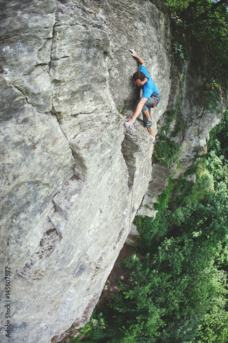 male rock climber. rock climber climbs on a rocky wall. man makes hard move