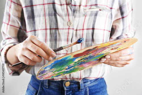 Woman holding palette of oil paints and painting brush, closeup