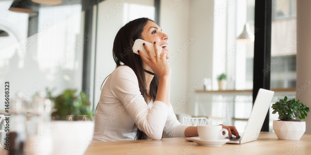 Happy woman having cell telephone conversation while sitting in cafe Happy woman having cell telephone conversation while sitting in cafe