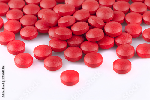 Red pills on a white surface. Red pills isolated on white background.
