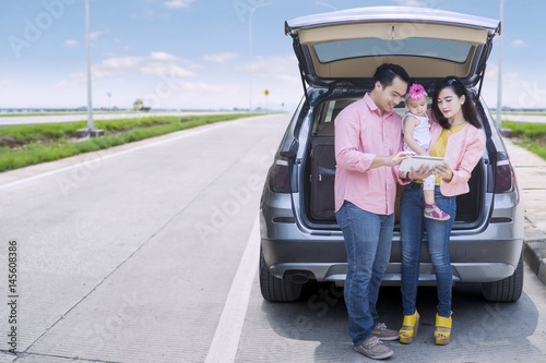 Family standing behind car © Creativa Images