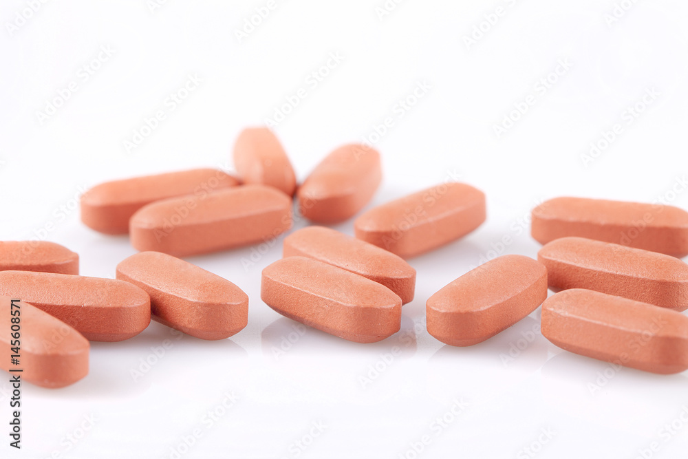 Ibuprofene pills on a white surface. Brown pills isolated on white background. Ibuprofene pills on a white surface. Brown pills isolated on white background.