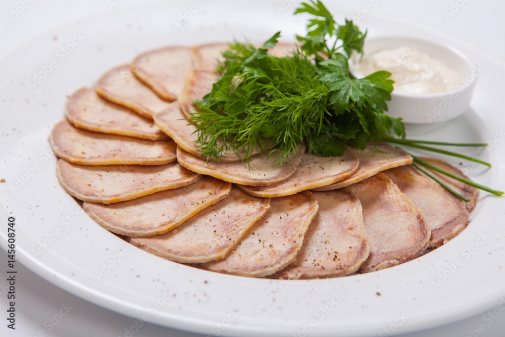 Slices of boiled beef tongue on a white plate Slices of boiled beef tongue on a white plate