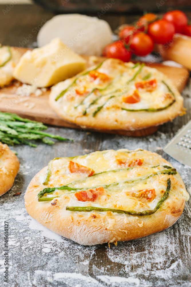 Mini pizza with asparagus. Traditional small pizza for personal eating filling with cheese, tomatoes and asparagus. Mini pizza with asparagus. Traditional small pizza for personal eating filling with cheese, tomatoes and asparagus.