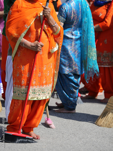 Barefoot women with long clothes sweep the way during the sikh c