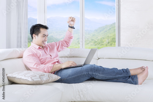Successful man raising hand on sofa