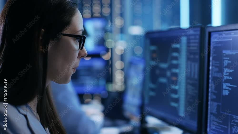 Close-up Footage of Female IT Engineer Working in Monitoring Room. She Works with Multiple Displays. Shot on RED EPIC-W 8K Helium Cinema Camera.