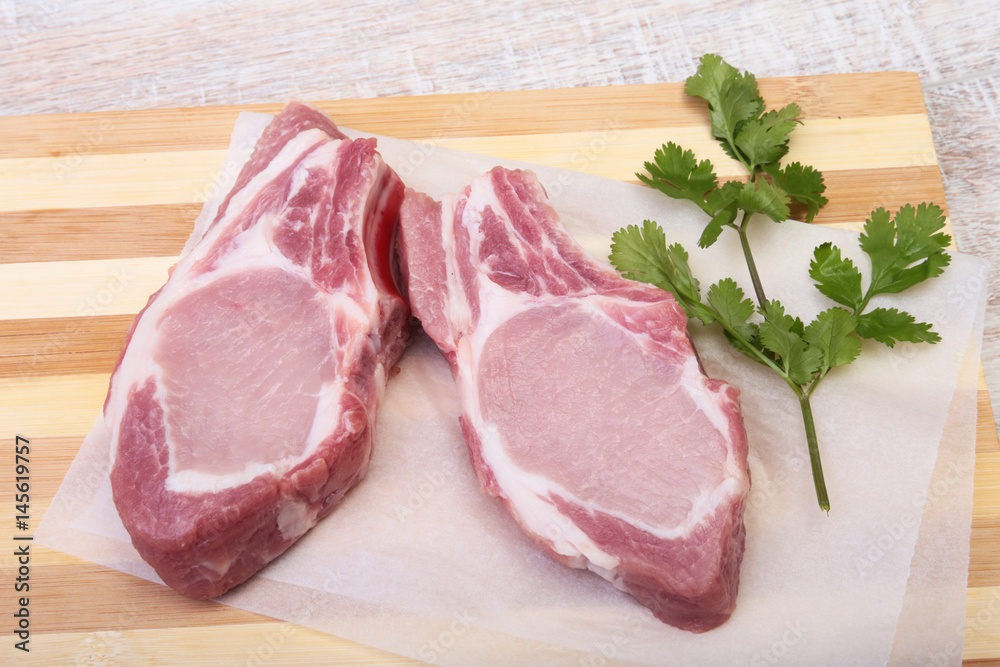 Raw pork chops, spices and basil on cutting board. Ready for cooking. Raw pork chops, spices and basil on cutting board. Ready for cooking.