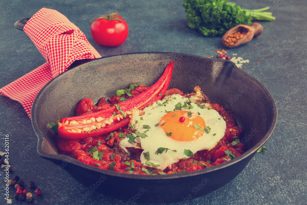 Ταπετσαρία A popular Mexican breakfast dish Huevos Rancheros, fried eggs and salsa on a black cast-iron skillet on gray-blue concrete background