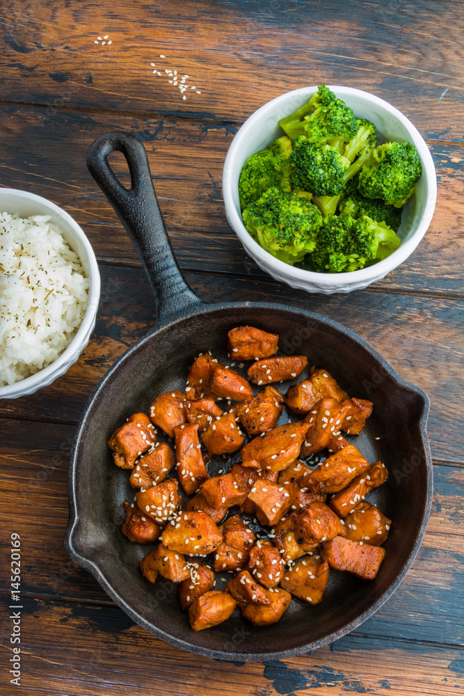 Φωτογραφία Chicken teriyaki pan-fried in a cast iron skillet  with garnish of rice and broccoli in white bowls