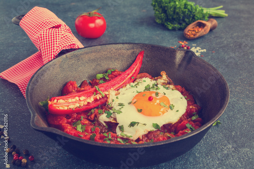 Bild auf Leinwand A popular Mexican breakfast dish Huevos Rancheros, fried eggs and salsa on a black cast-iron skillet on gray-blue concrete background