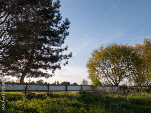 a fence a field some trees and a setting sun creating a beautiful scene relaxing and peace natural landscape
