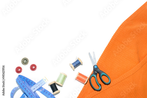 Coil with thread, scissors and ruler on a piece with a bright cloth, on a white background photo