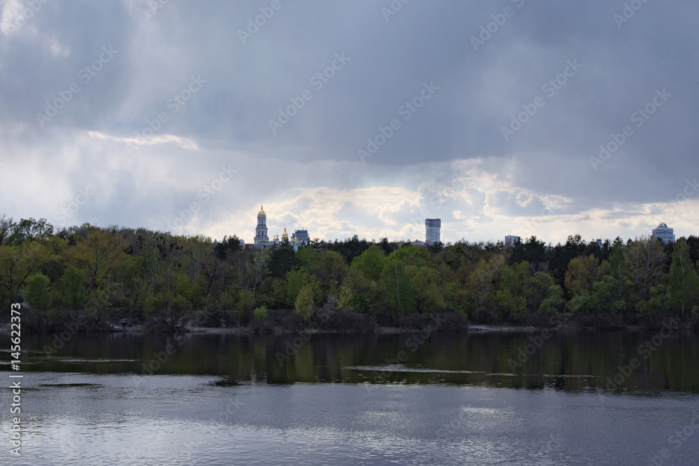 View of the right bank of the Dnieper. On the horizon you can see the bell tower of the Kiev-Pechersk Lavra. Cloudy spring day. Kiev. Ukraine