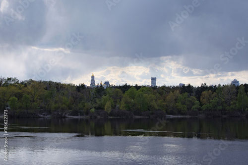 View of the right bank of the Dnieper. On the horizon you can see the bell tower of the Kiev-Pechersk Lavra. Cloudy spring day. Kiev. Ukraine