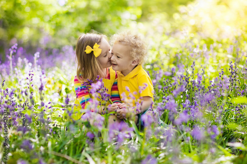 Kids playing in blooming garden with bluebell flowers © famveldman