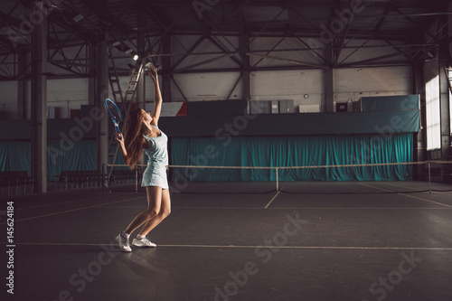 Full body portrait of young girl tennis player in action in a tennis court indoor © Vladimir