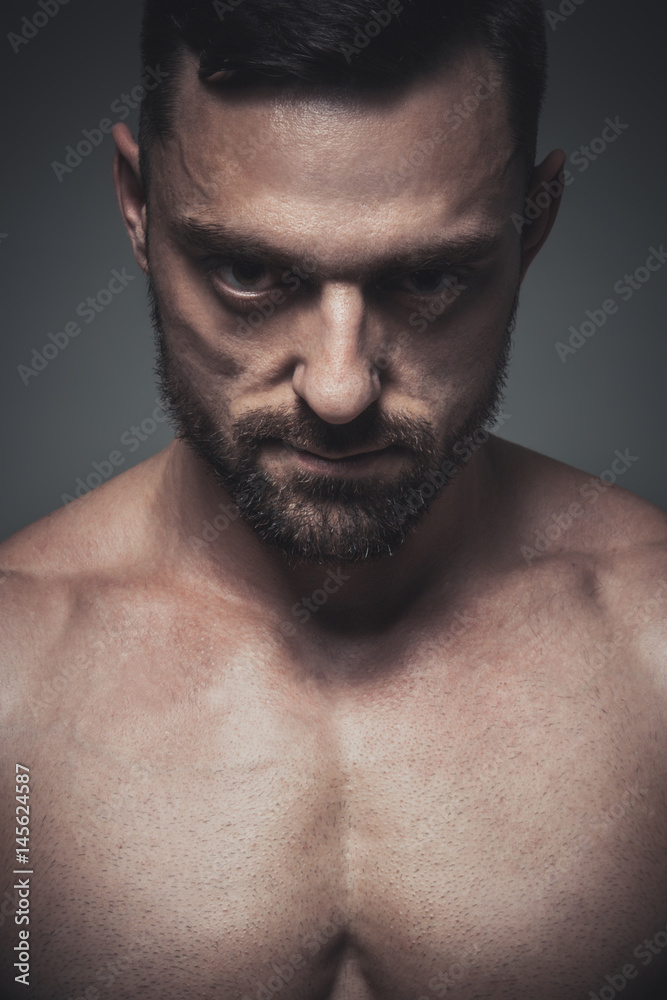 Portrait of muscle male model posing on grey background. Studio shoot. Portrait of muscle male model posing on grey background. Studio shoot.