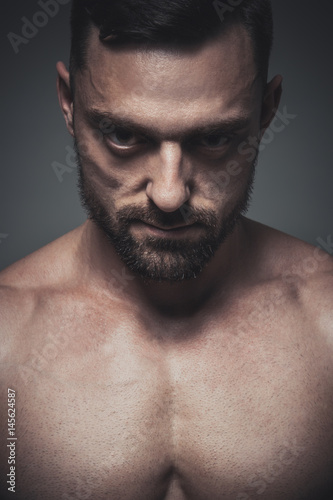 Portrait of muscle male model posing on grey background. Studio shoot.