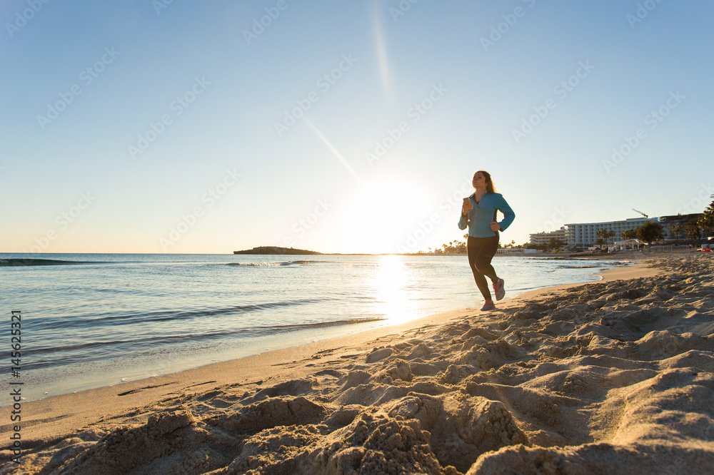 Fitness Woman Running by the Ocean at Sunset