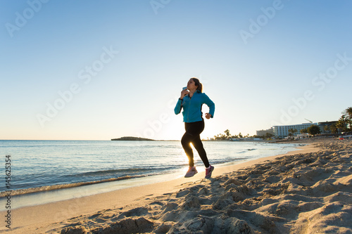 Fitness Woman Running by the Ocean at Sunset