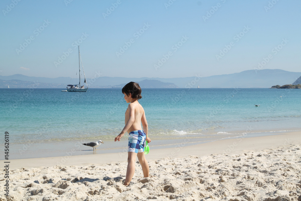 child in the beach looking to the sea