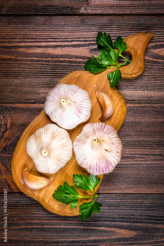Garlic cloves and garlic bulb on a wooden board on a brown background. Top view Garlic cloves and garlic bulb on a wooden board on a brown background. Top view