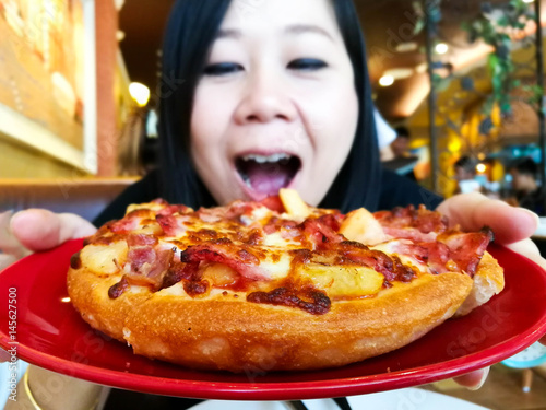 Woman eating pizza in restaurant with happy,Selective focus.