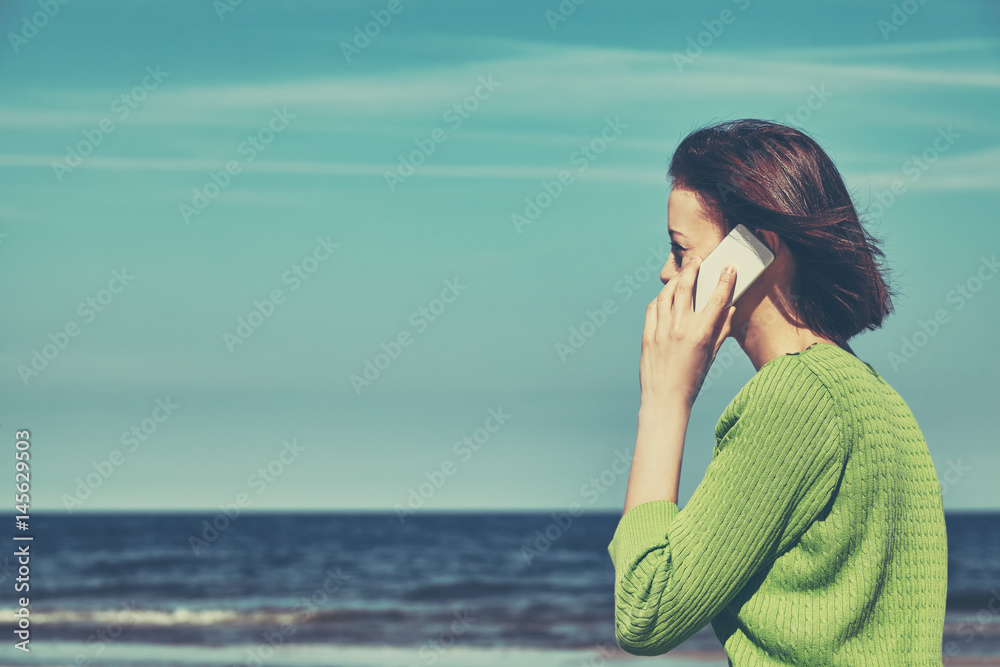 Retro stylized picture of woman talking on a phone on a beach. Retro stylized picture of woman talking on a phone on a beach.