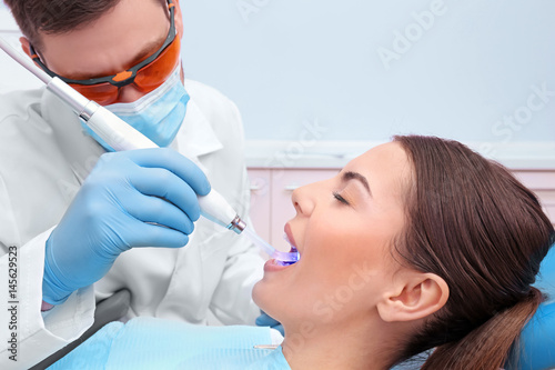 Dentist examining tooth of young woman in clinic