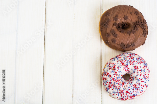 Delicious donuts on white wooden background
