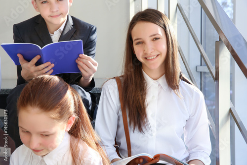 Happy pupils with books sit...