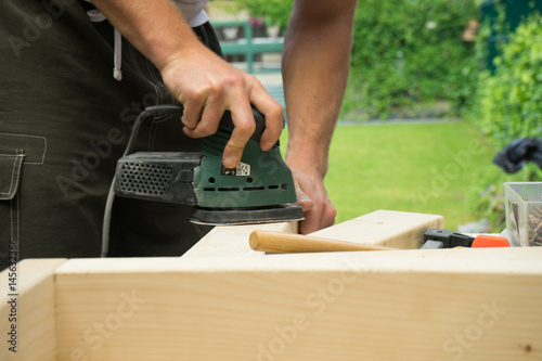 Man sanding wooden board DIY project in garden