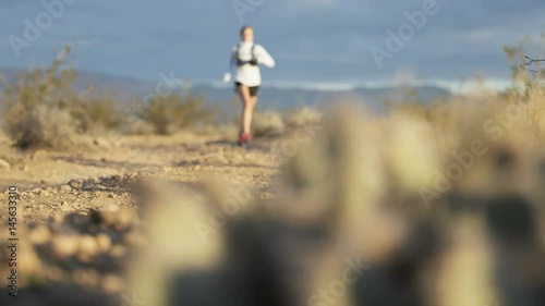 panning shot of girl trail running in desert