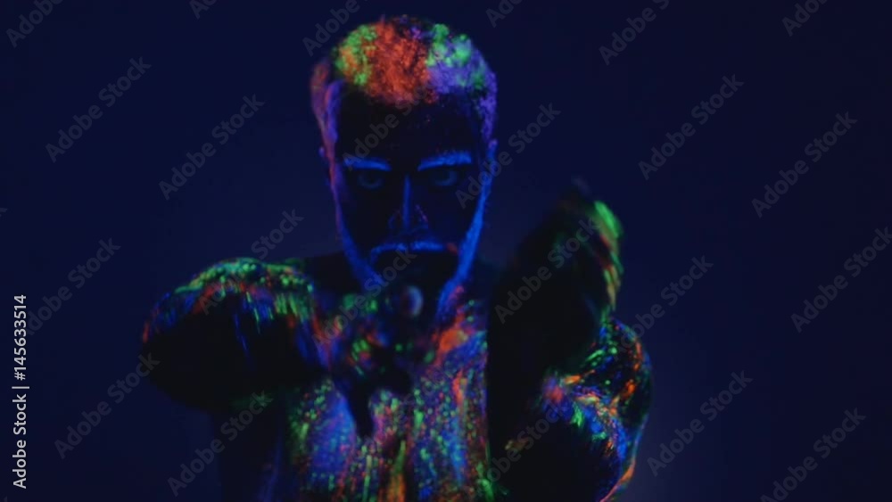 A man with a beard in the ultraviolet light. Magic passes with hands. A man with a beard in the ultraviolet light. Magic passes with hands.