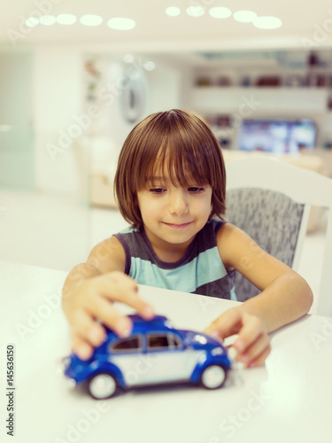 Happy kid at home with oldtimer car toy
