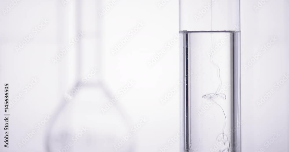 Translucent gel is dropped into test tube with liquid