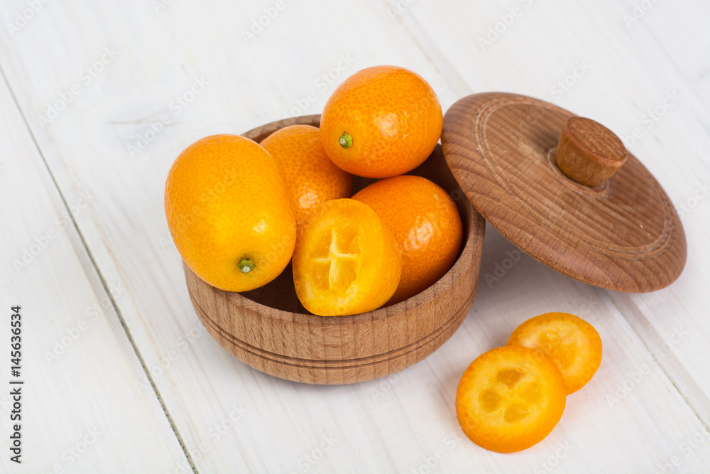 Small ripe orange kumquats on white wooden background